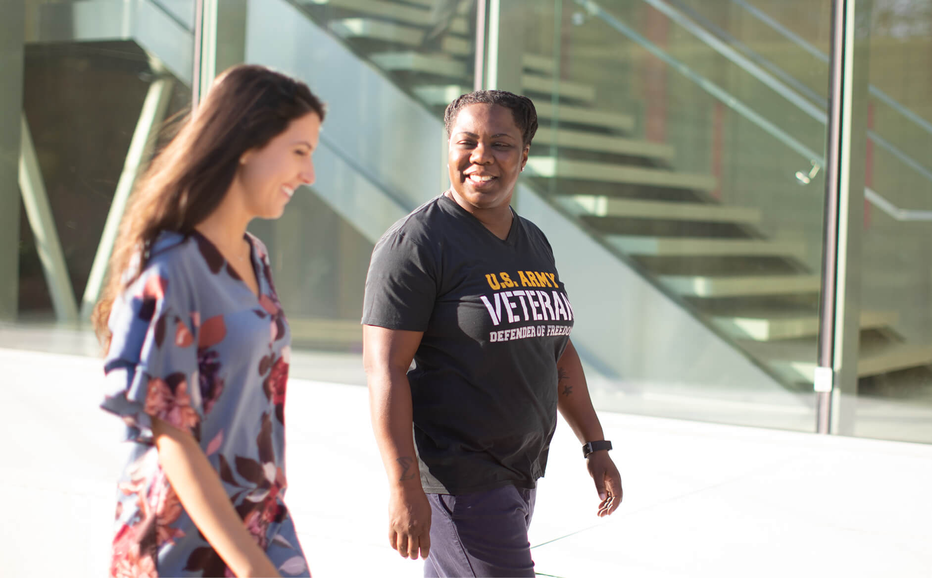 Two Capital One associates walking outside, one wearing a U.S. Army Veteran T-Shirt